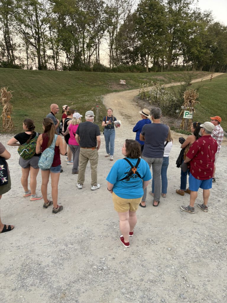 A group of walkers gathered on a gravel trail listening to a guide