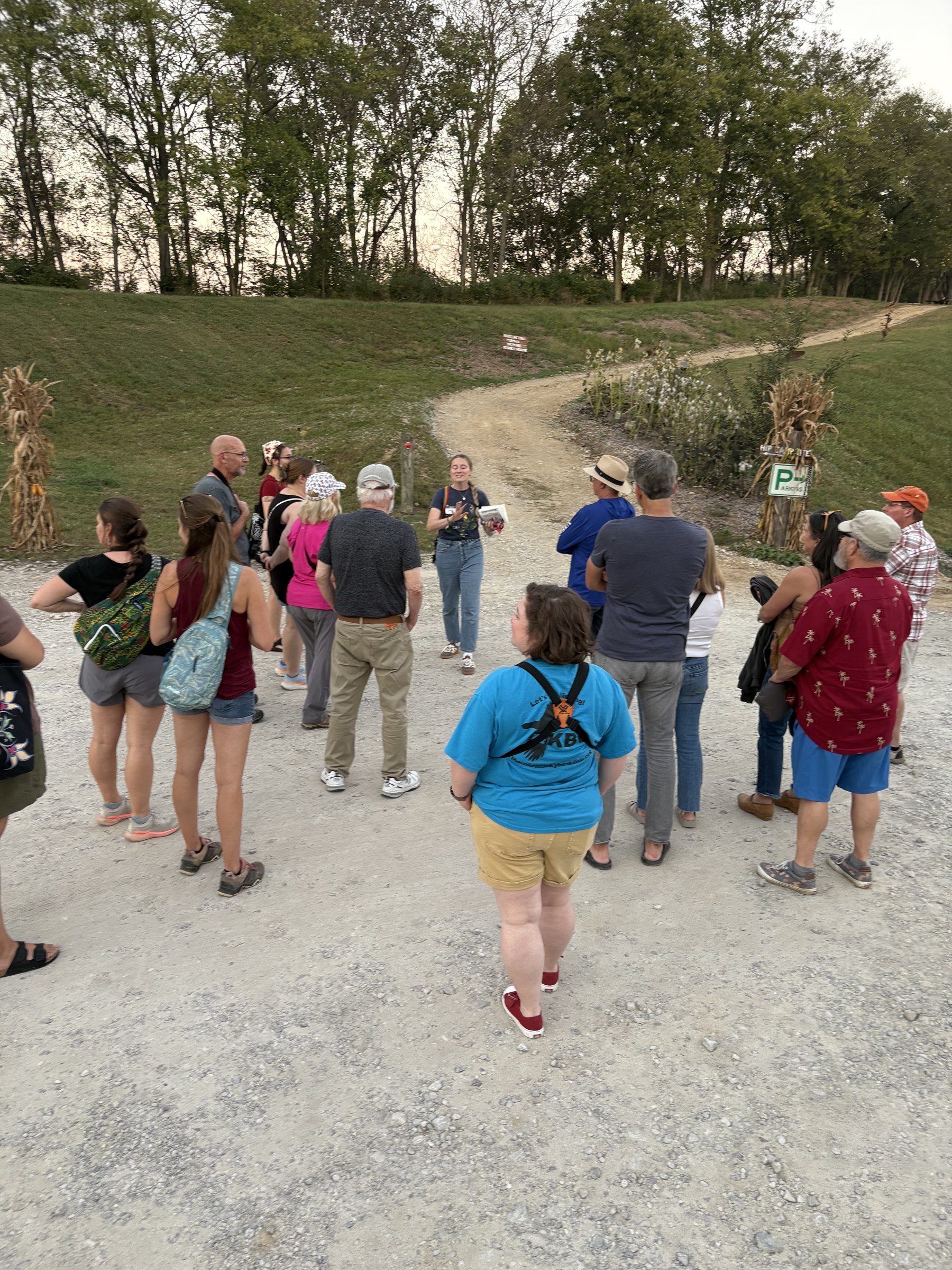A group of walkers gathered on a gravel trail listening to a guide